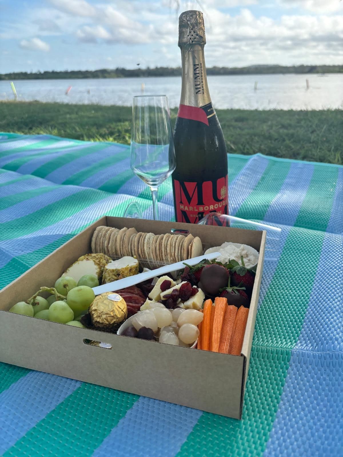 A catering box with a picnic spread by the water